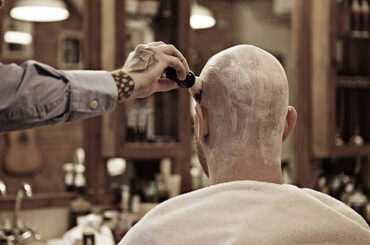 Tattooed barber with a bearded bald male client